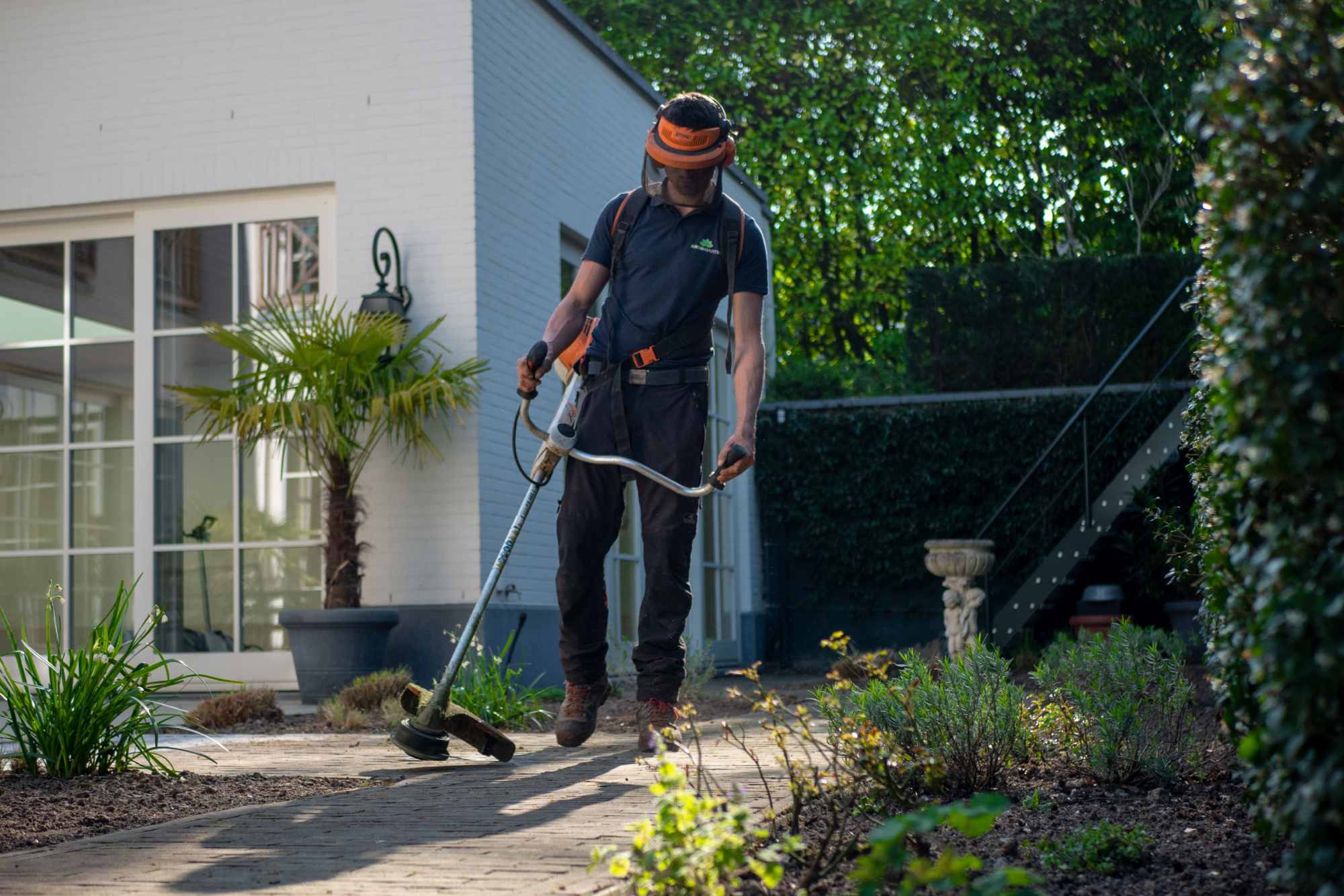 A gardener cutting the grass wearing protective equipment
