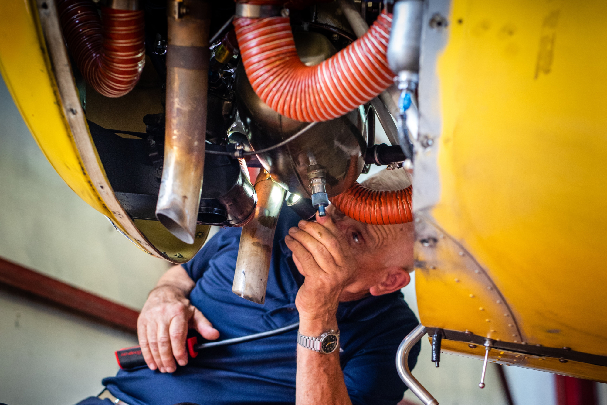 An old man repairing the engine of a plane